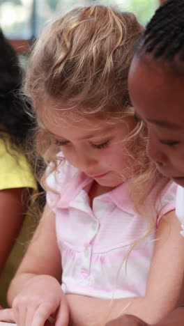 Vertical-video-of-Caucasian-and-African-American-girls-reading-together-at-school