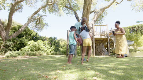 Glückliche-Afroamerikanische-Großeltern-Mit-Enkelkindern,-Die-Im-Garten-Fußball-Spielen,-In-Zeitlupe