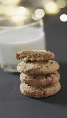 Vertical-video-of-mug-of-milk-and-christmas-cookies-and-copy-space-on-black-background