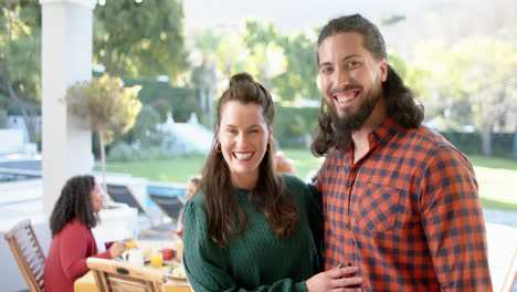 Two-happy-caucasian-male-and-female-friends-posing-during-celebration-meal-in-sunny-garden