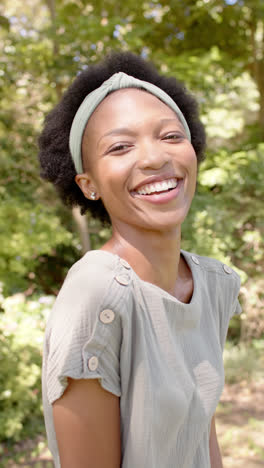 Vertical-video-of-portrait-of-happy-african-american-woman-in-garden,-in-slow-motion