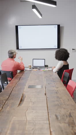 Vertical-video-of-diverse-male-and-female-colleague-in-casual-office-having-video-call,-copy-space