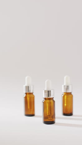 Vertical-video-of-dropper-serum-bottles-on-white-background-with-copy-space