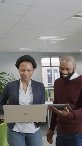 Vertical-video-of-happy-african-american-business-people-using-laptop-in-slow-motion