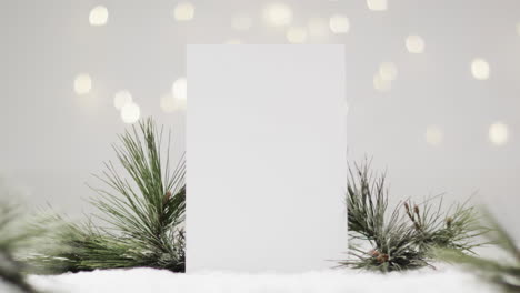 Video-of-christmas-decorations-and-white-card-with-copy-space-on-snow-background