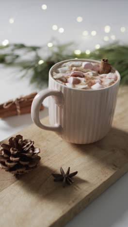 Vertical-video-of-mug-of-christmas-chocolate-with-marshmallows-and-copy-space-on-white-background