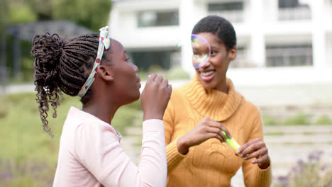 Feliz-Madre-E-Hija-Afroamericana-Soplando-Burbujas-En-El-Soleado-Jardín