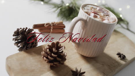 Texto-De-Feliz-Navidad-En-Rojo-Sobre-Piñas,-Canela-Y-Chocolate-Caliente-Navideño-Con-Malvaviscos