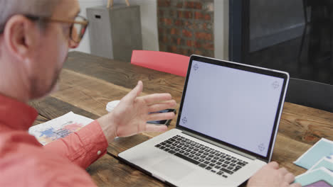 Senior-caucasian-male-designer-having-video-call-on-laptop-with-copy-space-on-screen,-slow-motion