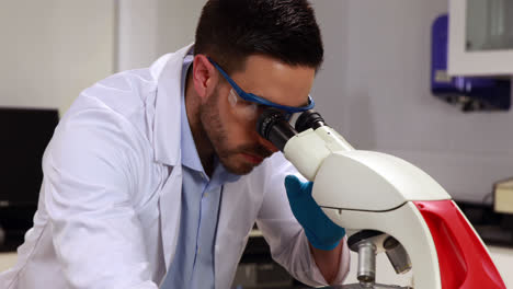 Joven-Científico-Mirando-A-Través-Del-Microscopio-En-El-Laboratorio