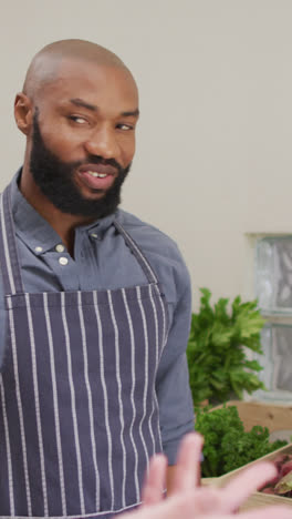 Video-of-happy-african-american-salesman-showing-organic-vegetables-to-caucasian-female-customer