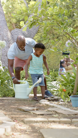 Vídeo-Vertical-De-Feliz-Abuelo-Y-Nieto-Afroamericanos-Haciendo-Jardinería,-En-Cámara-Lenta