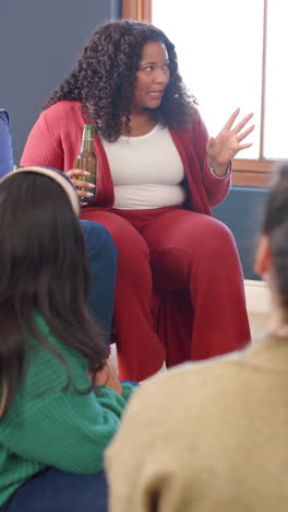 Vertical-video-of-happy-african-american-woman-sitting-with-beer-and-talking-with-friends