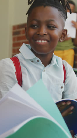 Video-of-happy-diverse-boys-holding-books-and-talking-in-front-of-school