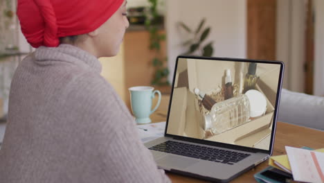 Mujer-Birracial-En-La-Mesa-Usando-Laptop,-Comprando-En-Línea-Productos-De-Belleza,-Cámara-Lenta