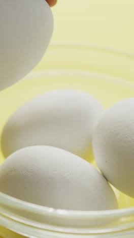 Video-of-close-up-of-biracial-man-putting-egg-into-bowl-on-yellow-background