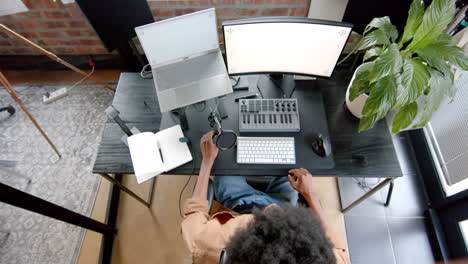 Over-head-of-african-american-man-podcasting-at-home,-slow-motion