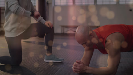 Animation-of-dots-over-diverse-trainer-and-fit-man-doing-plank-at-gym