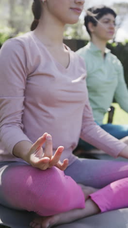 Feliz-Pareja-De-Lesbianas-Caucásicas-Practicando-Yoga-En-Un-Jardín-Soleado,-Cámara-Lenta