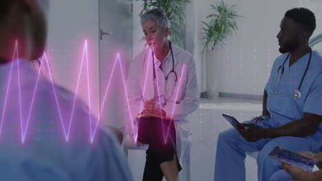 Animation-of-heart-rate-monitor-on-caucasian-female-doctor-discussing-with-healthworkers-at-hospital