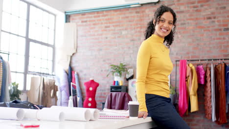 Portrait-of-happy-biracial-female-fashion-designer-crossing-arms-in-studio,-copy-space,-slow-motion