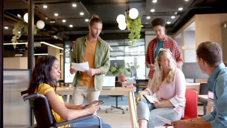 Happy-diverse-male,-female-and-disabled-colleagues-in-discussion-at-casual-office-meeting