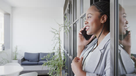 Happy-african-american-casual-businesswoman-talking-on-smartphone-in-office-lounge,-slow-motion