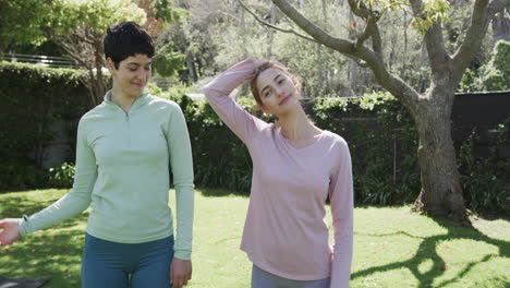 Happy-caucasian-lesbian-couple-stretching-in-sunny-garden,-slow-motion