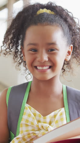 Video-of-happy-biracial-girl-standing-on-school-corridor