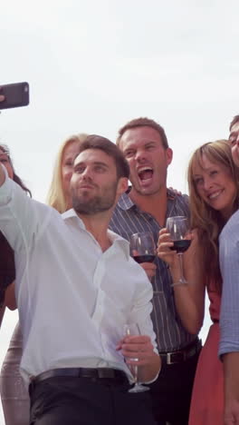 Vertical-video-of-a-Caucasian-group-enjoying-a-selfie-outdoors,-with-copy-space