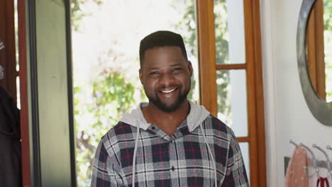 Feliz-Hombre-Afroamericano-Con-Barba-De-Pie-Y-Sonriendo-En-Casa-Soleada