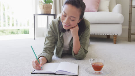 Happy-asian-woman-taking-notes-in-bedroom,-in-slow-motion