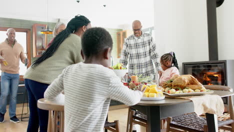 Fröhliche-Afroamerikanische-Mehrgenerationenfamilie,-Die-Essen-Beim-Thanksgiving-Dinner-Serviert,-Zeitlupe