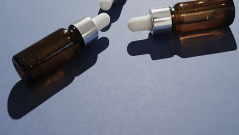 Close-up-of-three-glass-bottles-with-pumps-with-copy-space-on-blue-background