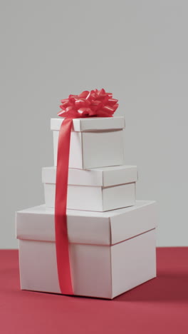 Vertical-video-of-stack-of-christmas-presents-and-copy-space-on-red-background