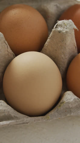 Video-of-overhead-view-of-brown-eggs-in-egg-carton-on-rustic-background