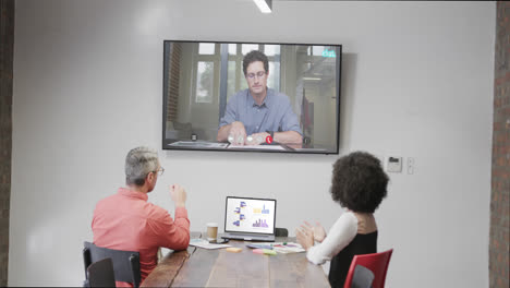 Diverse-business-people-on-video-call-with-caucasian-male-colleague-on-screen