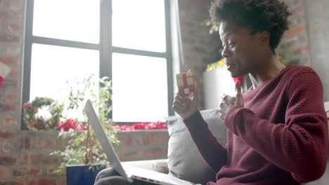 Happy-african-american-man-sitting-on-sofa-using-laptop-for-video-call-at-home,-slow-motion