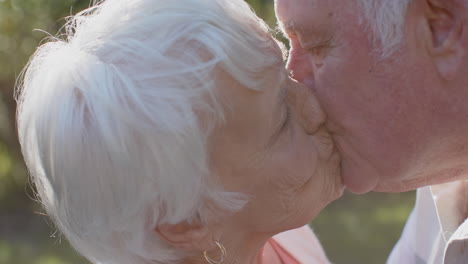 Feliz-Pareja-Caucásica-Mayor-Besándose-En-Un-Jardín-Soleado,-Cámara-Lenta