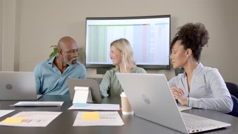 Diverse-business-people-using-laptops-at-conference-table-with-copy-space