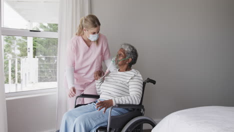 Caucasian-female-nurse-in-face-mask,-senior-african-american-woman-with-oxygen-mask,-slow-motion