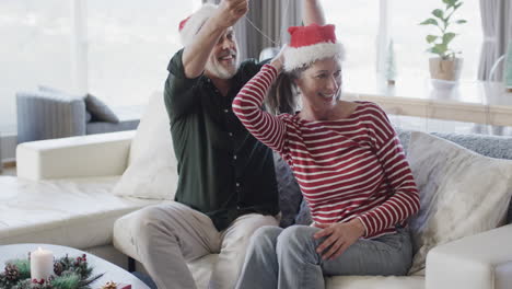 Hombre-Caucásico-De-Mediana-Edad-Con-Sombrero-De-Santa-Poniendo-Cadena-En-El-Cuello-De-Una-Mujer-En-Navidad,-Cámara-Lenta