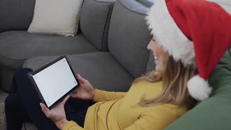 Fröhliche-Biracial-Frau-Mit-Weihnachtsmütze-Und-Tablet-Zu-Weihnachten,-Kopierraum,-Zeitlupe