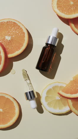 Vertical-video-of-make-up-bottle-with-pipette,-orange-slices-and-copy-space-on-white-background