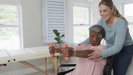 Caucasian-female-physiotherapist,senior-african-american-woman-in-wheelchair-exercising,-slow-motion