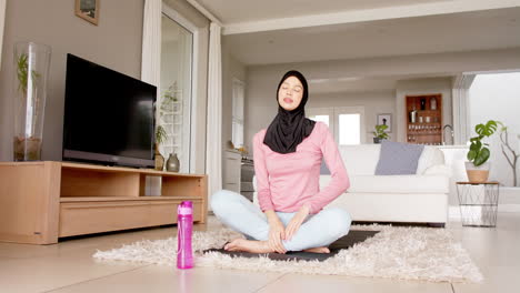 Mujer-Birracial-Enfocada-En-Hijab-Practicando-Yoga-En-Casa-Con-Espacio-Para-Copiar,-Cámara-Lenta