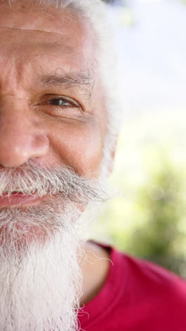 Vídeo-Vertical-Medio-Retrato-De-Un-Feliz-Hombre-Birracial-Mayor-Con-Barba-Blanca-Al-Sol,-Cámara-Lenta