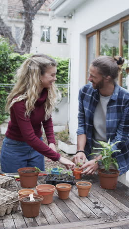 Video-Vertical-De-Una-Feliz-Pareja-Diversa-Plantando-Semillas-En-El-Jardín,-Cámara-Lenta