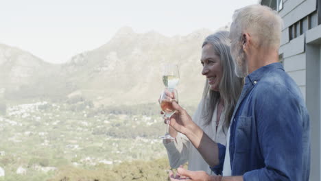 Feliz-Pareja-Caucásica-De-Mediana-Edad-Bebiendo-Vino-En-La-Terraza-De-Las-Montañas,-Cámara-Lenta