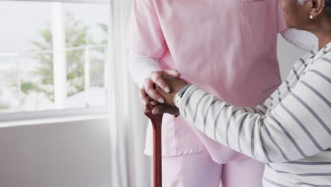 Caucasian-female-nurse-holding-hands-of-senior-african-american-woman,-copy-space,-slow-motion